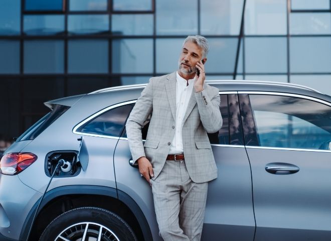 business man standing next to car on phone