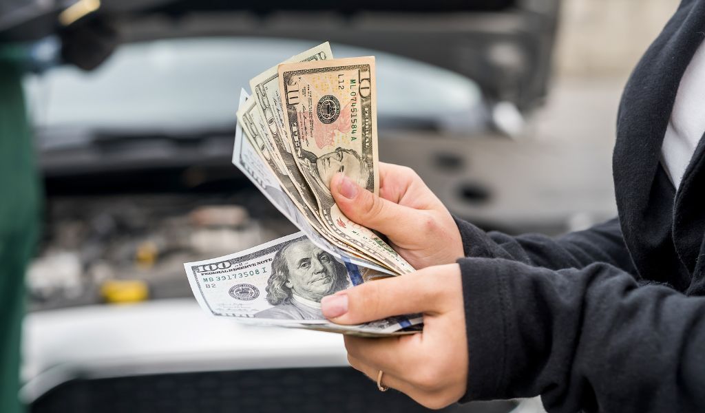 Man holding money paying for car repairs