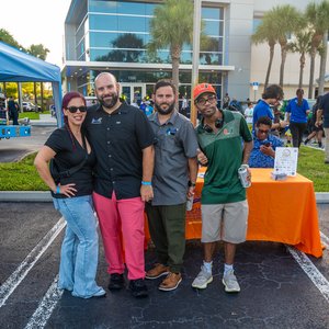 Smiling group in front of orange table outside